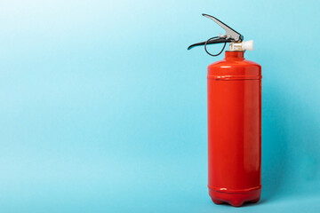 Obraz premium Fire extinguisher on the background of a blue wall. Fire protection, home fire extinguisher. home security concept. Place for text. Copy sleep.