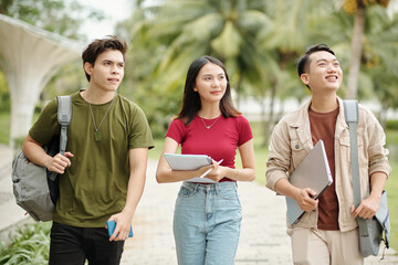 Group of happy students walking on campus and looking around