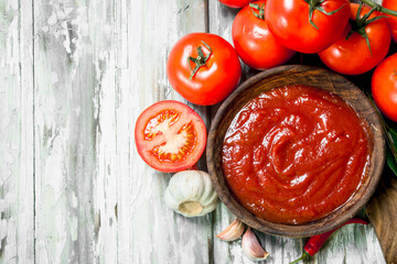 Tomato sauce in bowl and ripe tomatoes.
