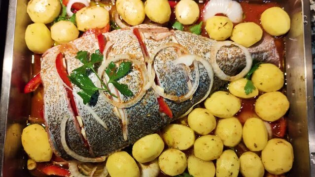 Gilt head bream fish prepared for the oven with potatoes and vegetables. Portuguese Mediterranean cuisine. Healthy seafood. 
