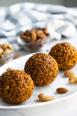 Energy bar nut balls cookie on white plate with almond and cashew. Recipe of simple homemade cookie with nuts full of protein and fats. Ketogenic diet or paleo diet dessert.