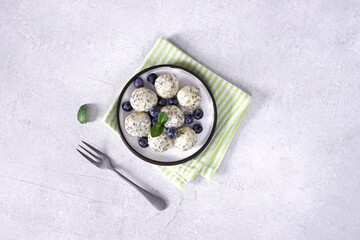Cottage cheese lazy dumplings with poppy seeds, blackberries, mint and sugar milk on a plate and linen napkin, concrete background, copy space, top view