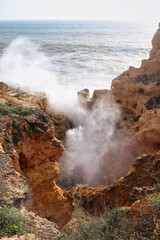 Water splashing over rocks at a beach in Portugal, Praia do Carvoeiro, on a warm winter day.