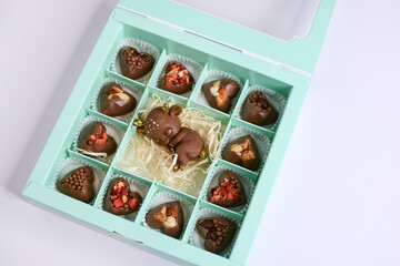 Chocolate cute fawn and candies with various fillings in a gift box on a light background. Chocolate candies