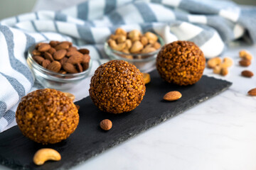 Healthy raw dessert, bliss balls of nuts cashew and almonds on black rock board. Energy balls for healthy eating. Gluten off, sugar free candies made of nuts.
