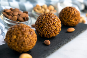 Cookie balls made of biscuit crumbs, cashew and almons nuts and caramel on black rock board. Easy recipe of homemade dessert without baking. Bliss balls for tea time.