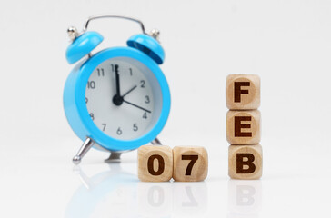 On a white background, a blue alarm clock and a calendar with the inscription - February 7