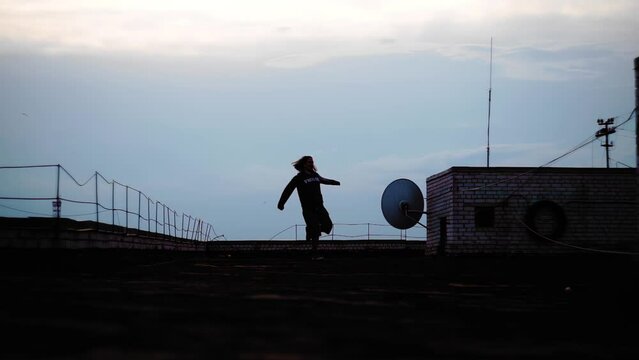 A man does sports and warm-up at sunset on the roof of the house. Very atmospheric shots of a big city