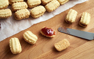 Filling homemade Christmas cookies with strawberry marmalade