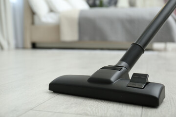 Hoovering floor with modern vacuum cleaner, closeup. Space for text