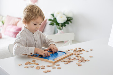 Preschool child, cute blond boy, playing with wooden numbers