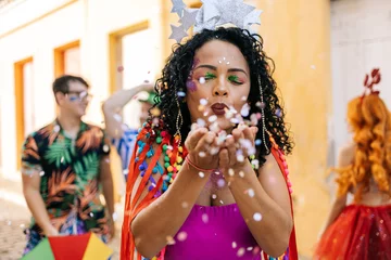Photo sur Plexiglas Carnaval Brazilian Carnival. Young woman enjoying the carnival party blowing confetti