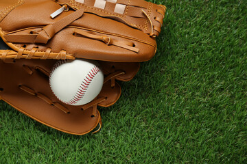 Catcher's mitt and baseball ball on green grass, top view with space for text. Sports game