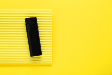 Stylish small pocket lighter with corrugated fiberboard on yellow background, top view. Space for text