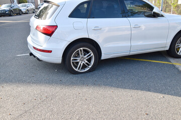 Fototapeta premium Small white car with a flat rear tire on an asphalt road