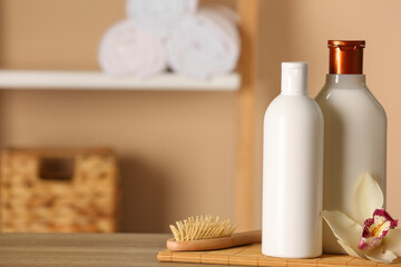 Bottles of shampoo, hairbrush and flower on wooden table in bathroom, space for text - obrazy, fototapety, plakaty