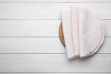 Delicious folded Armenian lavash on white wooden table, top view. Space for text