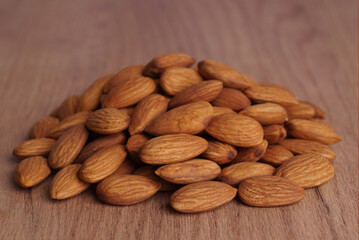 Pile of delicious almonds on wooden table, closeup