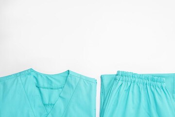 Light blue medical uniforms on white background, flat lay. Space for text