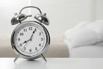 Silver alarm clock on white wooden table in bedroom, space for text