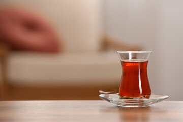 Glass with tasty Turkish tea on wooden table indoors, space for text