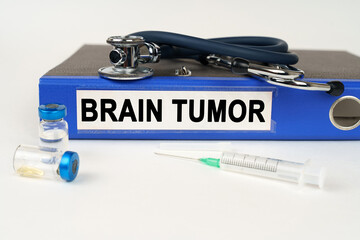 On a white surface, a syringe, a stethoscope and a folder with the inscription - Brain tumor