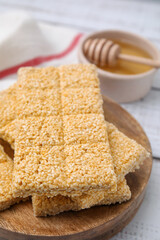 Wooden board with tasty sesame kozinaki bars on white table, closeup
