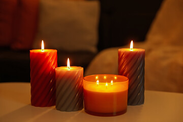 Burning candles on white table indoors. Cosy atmosphere