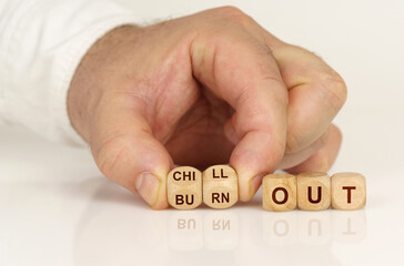 On the reflective surface in the hands of a man are cubes with the inscription - burn out to chill out