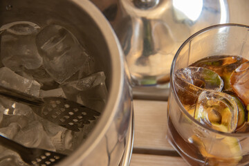 Bourbon glasses with lemon and ice cubes, Bottle And Ice Bucket On Table