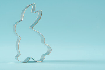 Easter bunny on blue background. Happy Easter Day concept. Minimal Easter concept. Space for text. Easter Cookie Cutter on baking background.