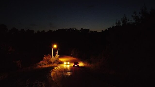 drone view of cars passing on a dark road at night