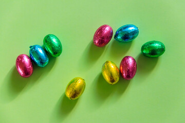 Easter chocolate eggs in foil on green background. Top view