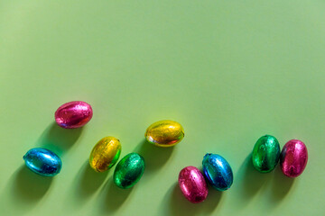 Easter chocolate eggs in foil on green background. Top view