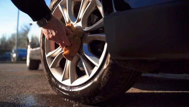 Close up of hand Detailed cleaning brush rim wheels. The brush washes the car wheel with soap. Rubs on the surface, wash dirty rims. Wash car after traveling and holiday.