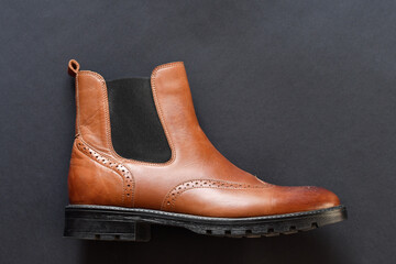 Light tan chelsea men boots on dark grey background. Copy space.