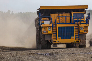 Large yellow dump trucks engaged in the transportation of rock mass in the quarry for mining. Machinery and equipment for iron ore mining