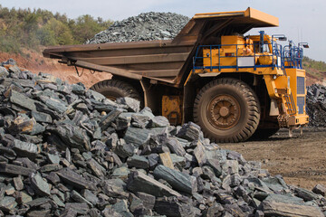 Large yellow dump trucks engaged in the transportation of rock mass in the quarry for mining. Machinery and equipment for iron ore mining