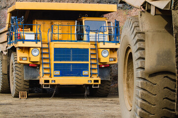 Large yellow dump trucks engaged in the transportation of rock mass in the quarry for mining. Machinery and equipment for iron ore mining