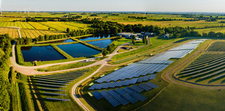 Panorama view of environmentally friendly installation of photovoltaic power plant and wind turbine farm situated by landfill.Solar panels farm built on a waste dump and wind turbine farm.