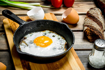 Fried egg in a pan with bread, tomatoes and green onions.