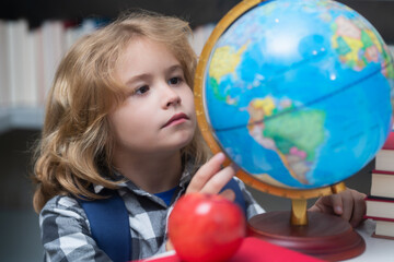 School kid looking at globe in library at the elementary school. Child from elementary school. Pupil go study. Clever schoolboy learning. Kids study, knowledge and education concept.