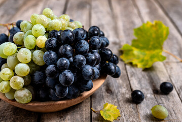 Bowl with grapes on wooden background