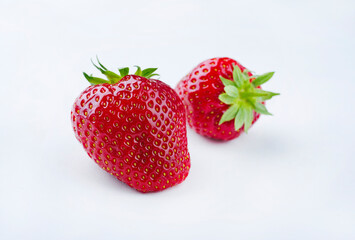 Zwei reife rote Erdbeere aus biologischem Anbau angeboten als close-up auf einem weißem Board mit Textfreiraum 