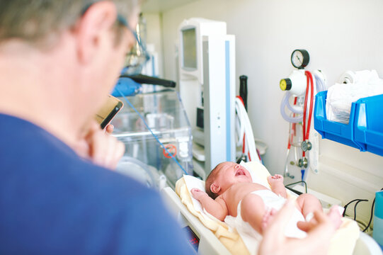 Crying Newborn Baby On Weight Scale In Hospital, First Days Of Life