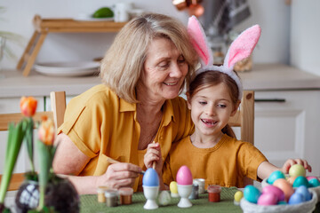 Happy easter family elderly grandmother and little granddaughter with rabbit ears are preparing for...