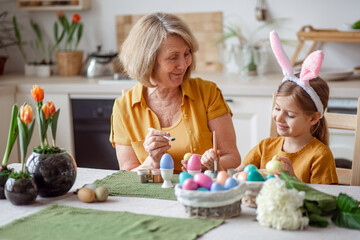 Happy easter family elderly grandmother and little granddaughter with rabbit ears are preparing for...