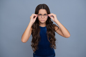 Serious teenager girl. Tennager child girl wear eyeglasses looking at camera with confidence over yellow background, copy space. Kid get eyesight.