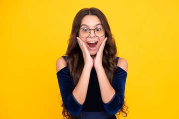 Shocked teenager child with amazed look on yellow background, amazement. Surprised teenager girl....