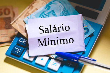  Salário Mínimo em Português do Brasil escrita em um pedaço de papel sobre uma calculadora com...